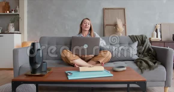 美丽快乐年轻健康的金发女性在家工作的肖像使用笔记本电脑隔离自我隔离的概念视频的预览图