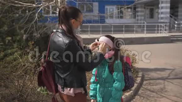 母亲戴着保护面具陪伴女儿戴着保护面具上学疫的风险这就是视频的预览图