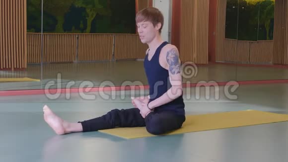一个年轻人开始上瑜伽课他把脚放在头后面然后站在他的手上4K视频的预览图