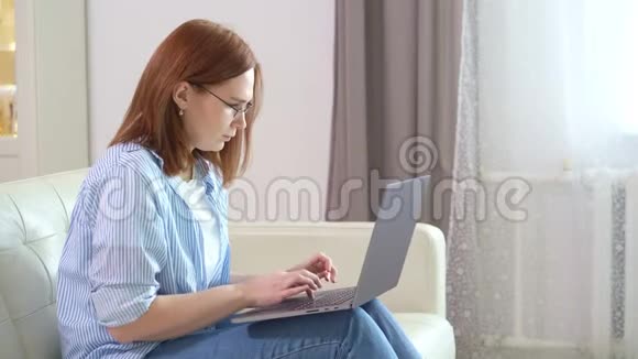 女自由职业者在家里的沙发上打字视频的预览图