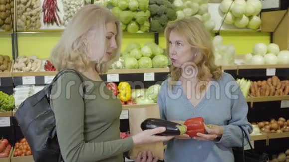 高加索族妇女在杂货店讨论茄子和红椒自信的家庭主妇买新鲜的有机食品视频的预览图
