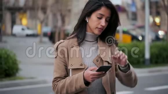 漂亮的年轻女人在手机上发短信在路边等着她的手表视频的预览图