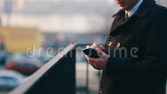 穿着黑色外套的商人站在街上用智能手机在电话里冲浪视频的预览图