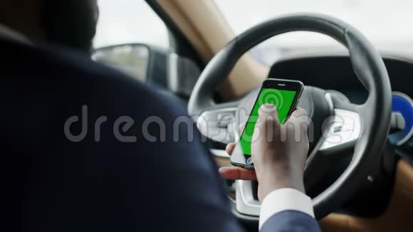 在汽车上使用绿色屏幕电话的人的背面视图坐电话的非洲男人视频的预览图