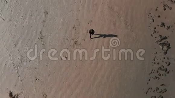 空中漂亮的体操女子在沙滩上练习背手弹簧穿黑色毛衣和靴子视频的预览图