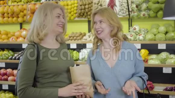 积极的白人资深家庭主妇在杂货店里闲聊和大笑成年女性聊天视频的预览图