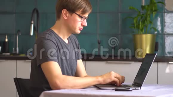 一个男人在家里用笔记本电脑在厨房工作远程工作概念视频的预览图