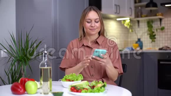 迷人的年轻女性使用智能手机拍摄蔬菜视频的预览图