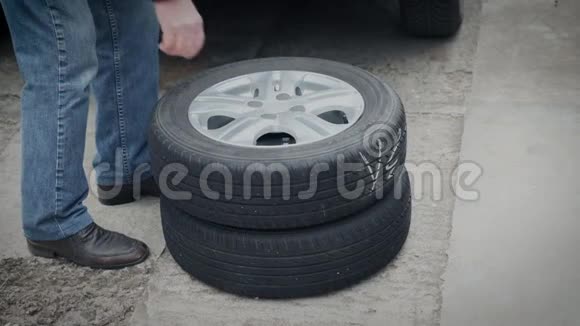 一个人把汽车的轮子装进后备箱用冬天代替夏天的轮胎视频的预览图