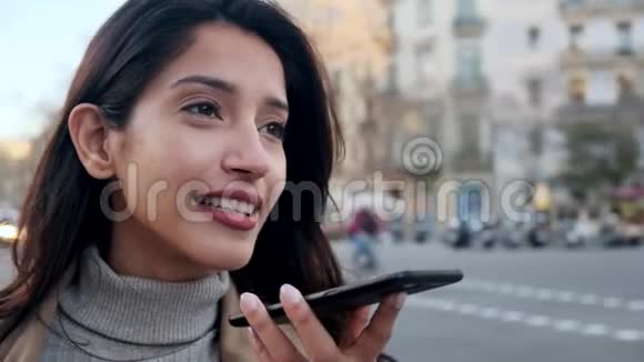 漂亮的年轻女人站在街上用手机和免费系统说话视频的预览图
