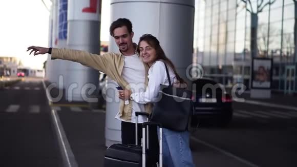 时髦的年轻夫妇带着行李站在机场停车场拿着手提箱待车后到达男子视频的预览图