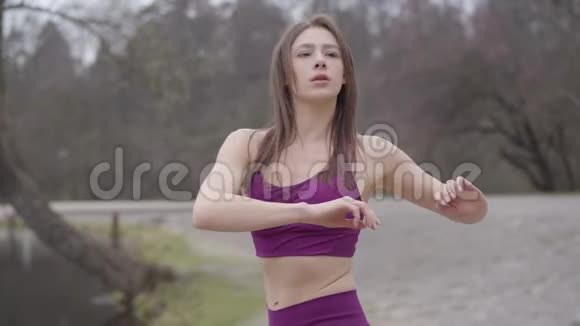 美丽的黑发女运动员早晨在户外伸展穿紫色运动服的瘦小女人视频的预览图