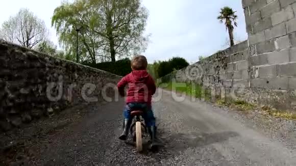 小蹒跚学步的男孩骑平衡自行车慢动作后景视频的预览图
