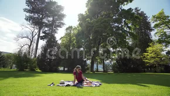 美丽的年轻女子戴着太阳镜在阳光明媚的春天在城市公园野餐视频的预览图