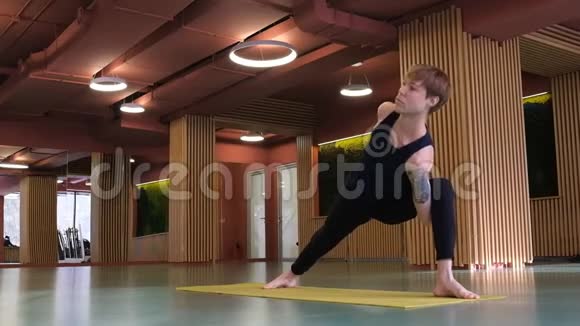 一个手臂肌肉发达纹身的帅哥正在健身房做瑜伽它能保持平衡增强肌肉视频的预览图