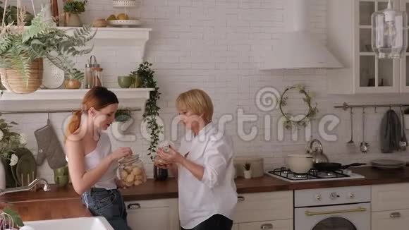 年长的母亲和一个成年的女儿在厨房里他们喝茶和饼干视频的预览图