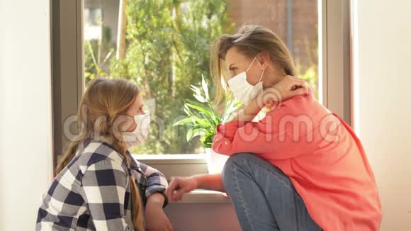 一位年轻女子和一位戴着医用口罩的学龄女孩正在窗边交谈检疫视频的预览图