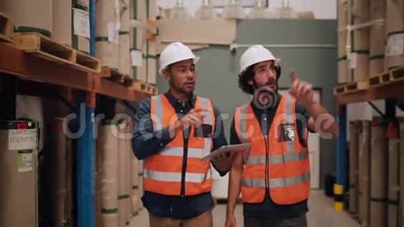 两名穿着安全帽和反光夹克的仓库工作人员负责保管仓库的制成品细节视频的预览图