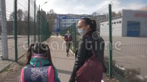 母亲和女儿带着一个戴着防护面具的学校背包走在街上一个十几岁的女孩视频的预览图