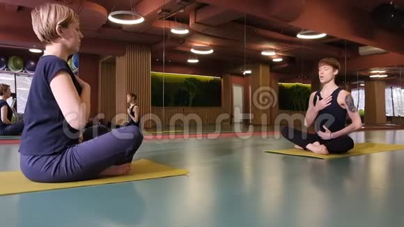 一个年轻人和一个女孩在做瑜伽个别课程做一个呼吸练习广角镜头在一个视频的预览图
