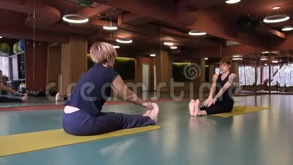 两个人正在大厅的垫子上做瑜伽一男一女坐在对面进行练习角度视频的预览图