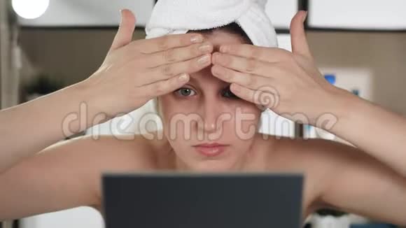 面部皮肤按摩带毛巾和镜子的漂亮女孩用她的额头做面部按摩视频的预览图