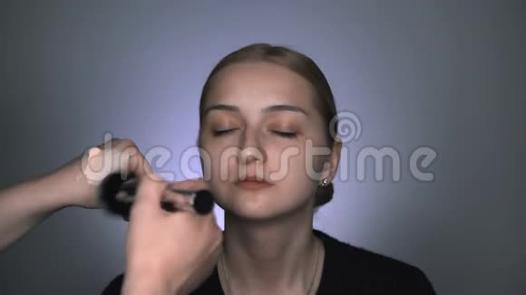 化妆师为美容工作室的年轻女性制作专业化妆化妆师用大的粉末视频的预览图