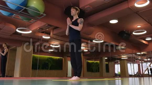 大厅里的哈莎瑜伽课一个年轻可爱的家伙表演阿纳斯站在他的手上他的腿缩起来视频的预览图