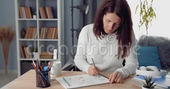 成熟的女人用彩色铅笔在相册里画画视频的预览图