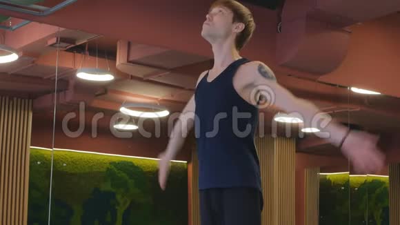 一个身材苗条灵活的年轻可爱的家伙做瑜伽他手臂上有一束百合花的纹身概念视频的预览图