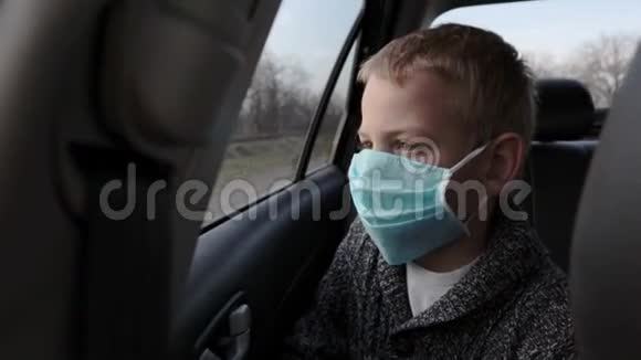 一个悲伤的十几岁男孩戴着医疗面具看着车窗外的肖像视频的预览图