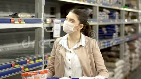 带着医用口罩的女孩在市场上走来走去推满了手推车视频的预览图