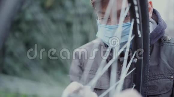 一个十几岁的孩子在他家的院子里用医用口罩修理自行车视频的预览图