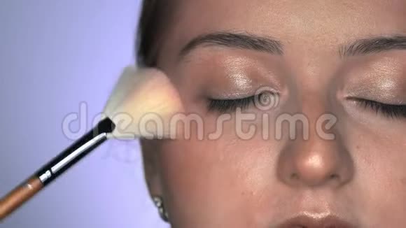 化妆师为美容工作室的年轻女性制作专业化妆化妆师用刷子涂闪光视频的预览图