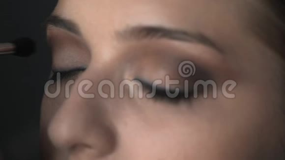 化妆师在美容工作室为年轻女性制作专业化妆的宏观镜头化妆师用刷子视频的预览图