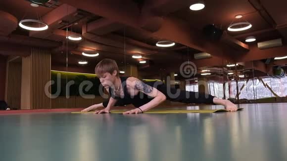 一个欧洲外表的年轻人从事瑜伽他在健身房的地板上伸展广角射击视频的预览图