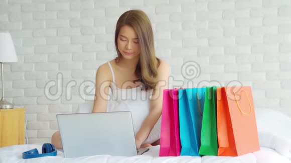 美丽迷人的亚洲年轻女性躺在床上使用电脑笔记本电脑视频的预览图