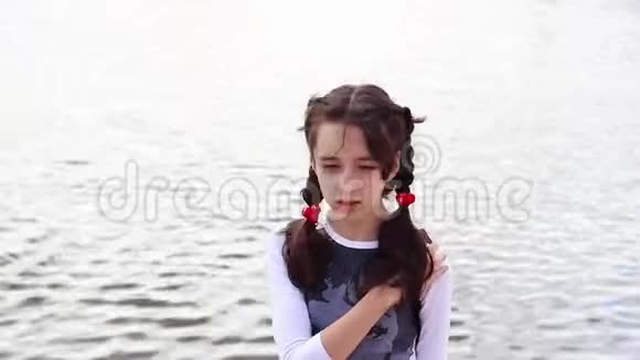 在温暖的天气里一个漂亮的女孩带着背包在水库附近散步视频的预览图
