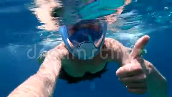 戴着面具的幸福女人在红海里邋遢地竖起大拇指视频的预览图