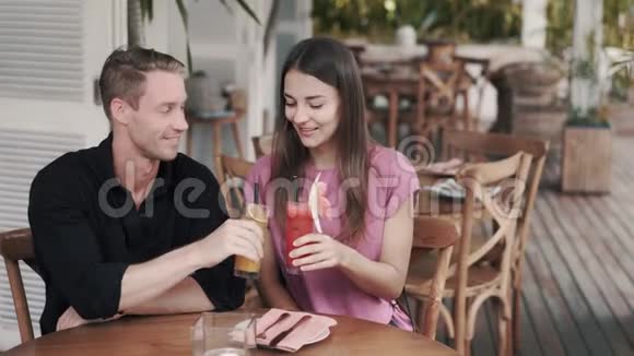 年轻夫妇在时尚的咖啡馆里喝新鲜果汁看着相机微笑视频的预览图