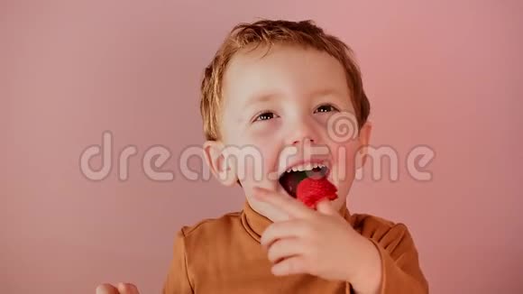 一个积极开朗的男孩吃红草莓的肖像视频的预览图