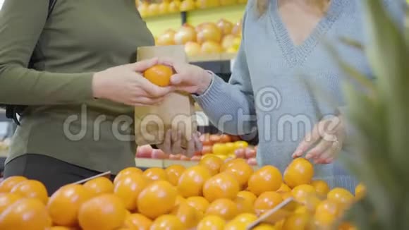 两位在杂货店里挑选橘子的不可辨认的女性顾客白种人成年女性选择新鲜有机视频的预览图