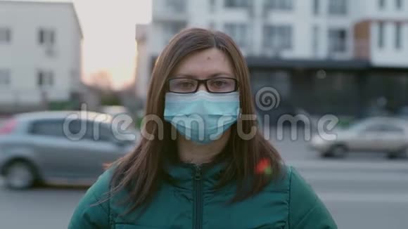 一个戴着眼镜和医用口罩的年轻女孩站在街上视频的预览图