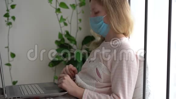 冠状病毒流行的检疫一个被感染的蒙面妇女在家里用笔记本电脑工作视频的预览图