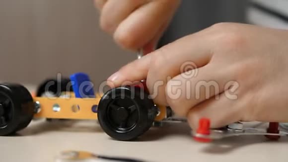 一个小男孩用一个金属建筑套件建造了一个汽车模型扭曲了零件特写孩子手视频的预览图