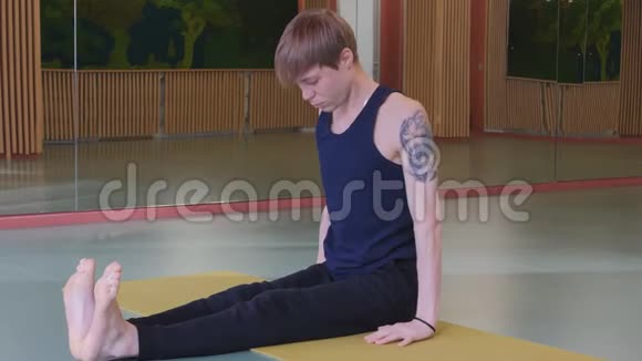 运动工作室里的垫子上的瑜伽一个肩上有纹身的年轻男子站在他的手上弯下腰视频的预览图
