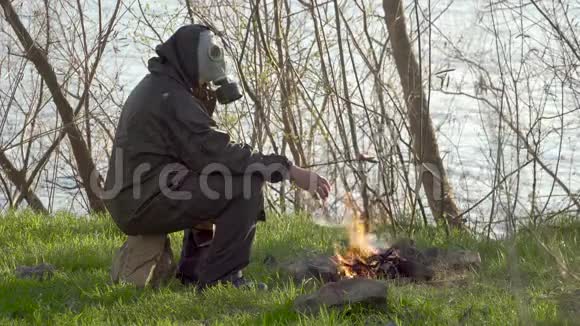 一个戴防毒面具的人在篝火旁炸香肠视频的预览图
