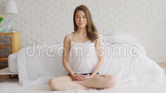 迷人的亚洲女性在醒来后在卧室练习瑜伽莲花姿势冥想视频的预览图