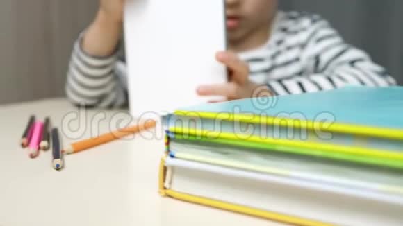一个孩子坐在桌子旁看着平板电脑上的东西自我孤立社会的流行视频的预览图