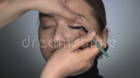 化妆师为美容工作室的年轻女性制作专业化妆化妆师将黑色眼线涂于视频的预览图